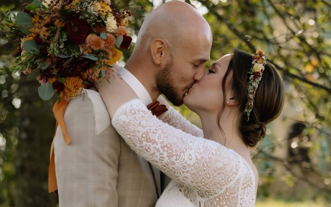 Novomanželé a jejich polibek, nevěsta drží v ruce svou svatební kytici