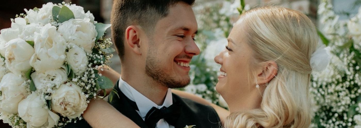 nevěsta objímající ženicha s kyticí v ruce