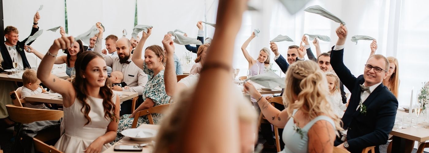 hosté vítají novomanžele pomocí látkových ubrousků, kterými mávají nad hlavami